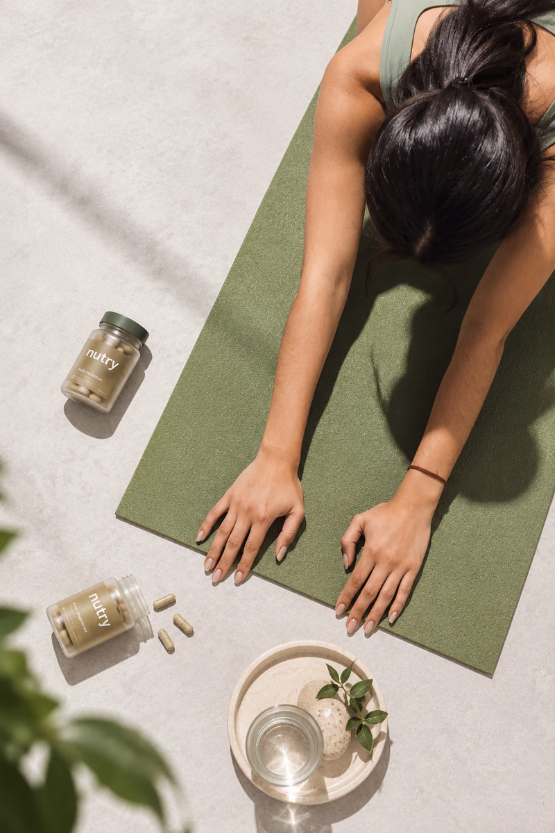 Woman stretching on a green yoga mat next to Nutry vitamin jars