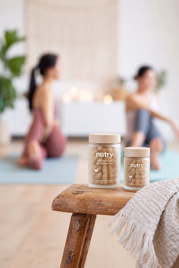 Two women doing yoga behind a stool with Nutry jars
